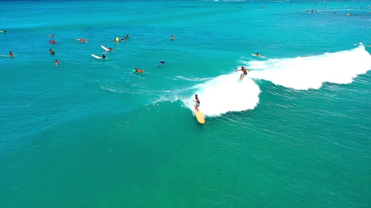 在阳光明媚的日子里，人们在海上享受冲浪的航拍镜头——夏威夷的威基基视频下载