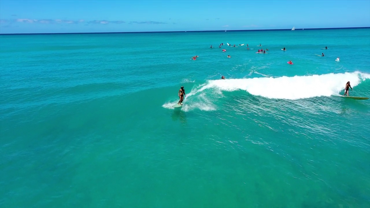 空中向后拍摄的男人和女人在阳光明媚的日子度假期间在海上冲浪-怀基基，夏威夷视频下载