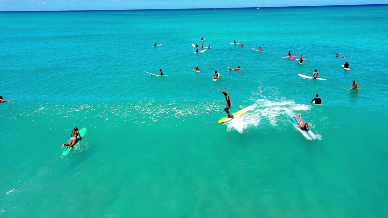 在阳光明媚的日子里，男人和女人在海里冲浪的航拍向后镜头——夏威夷的威基基视频下载