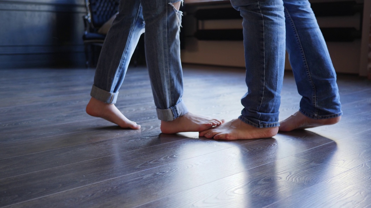穿着牛仔裤的赤脚情侣腿走在拼花地板上，彼此相遇视频下载