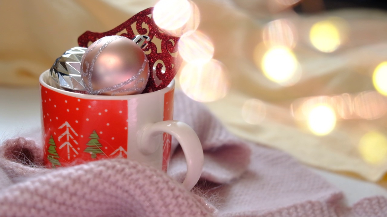 圣诞组成。圣诞小球装饰杯，温暖的钩针围巾和散景灯背景。圣诞节，新年，寒假的概念。视频素材