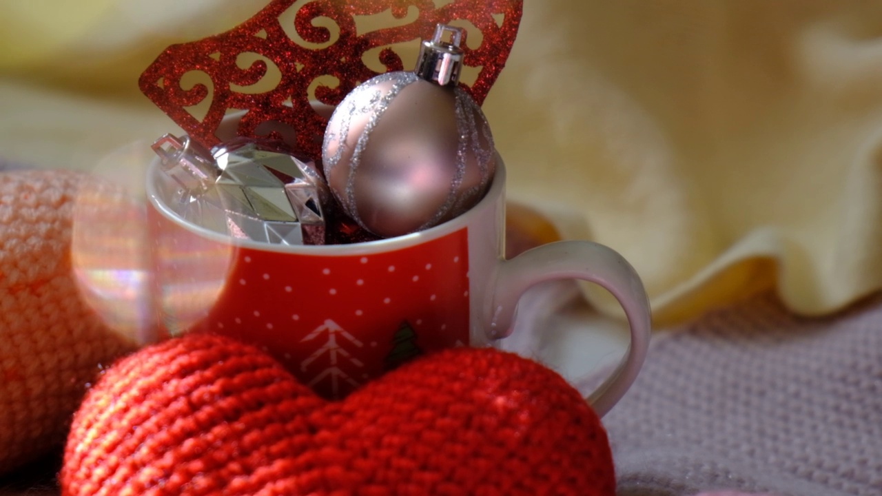 圣诞组成。圣诞小球装饰杯，温暖的钩针围巾和散景灯背景。圣诞节，新年，寒假的概念。视频素材