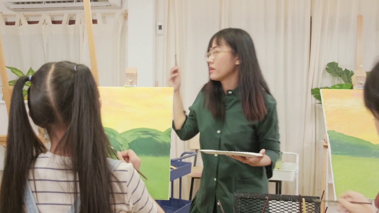 一位亚裔女老师在美术教室里教孩子们关于亚克力画的知识。视频下载
