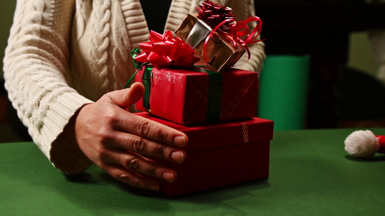 一个女人把圣诞礼物一一放在一张绿色的桌子上的特写。圣诞快乐和新年快乐的概念视频素材