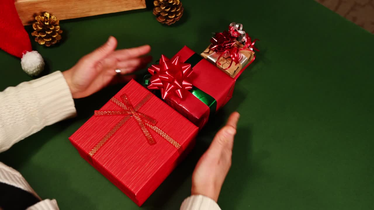 俯视图妇女堆叠圣诞礼盒，一个对一个，并围绕在绿色背景复制广告空间。视频下载