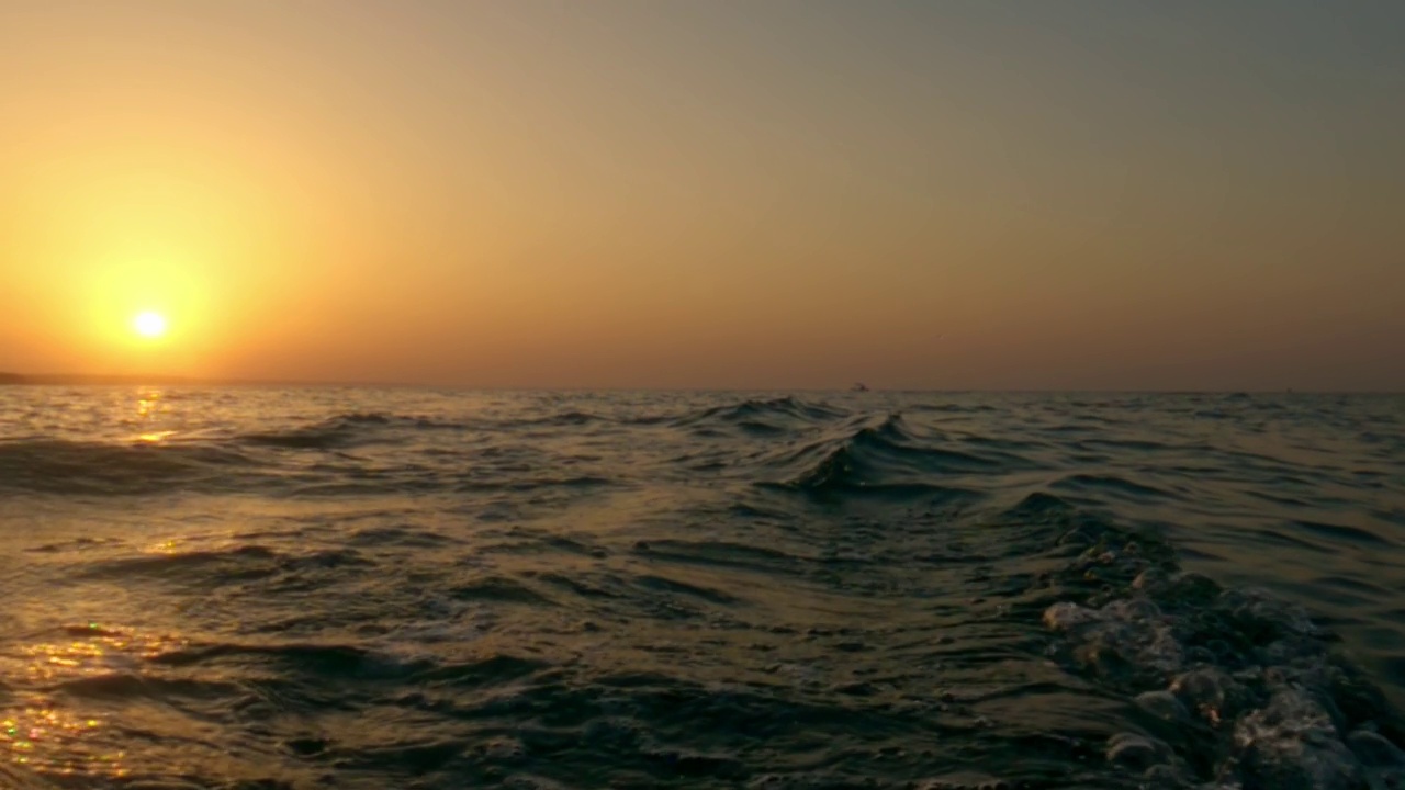 浪漫的日落在海水，低角度海水表面fpv pov向后移动的慢动作视频素材