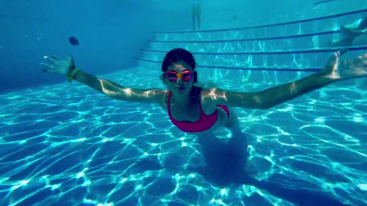 水下的一个小女孩潜水员跳舞在游泳池的气泡云。视频下载