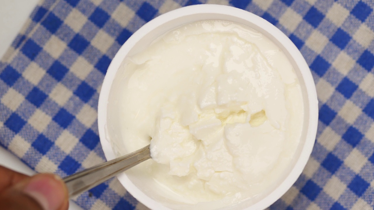 用勺子舀出新鲜的酸奶放在桌子上的碗里视频下载