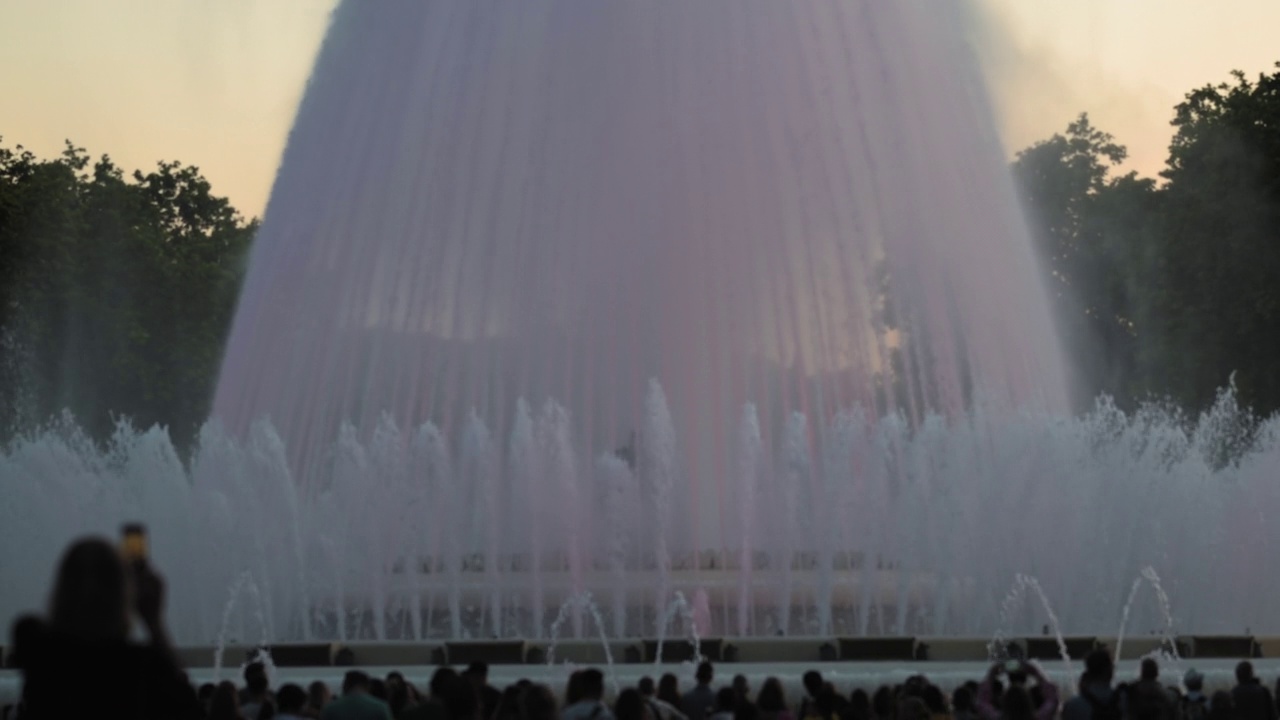 在西班牙加泰罗尼亚的巴塞罗那，蒙juic歌唱魔术喷泉表演的模糊日照。在前景剪影的人。高质量4k镜头视频素材