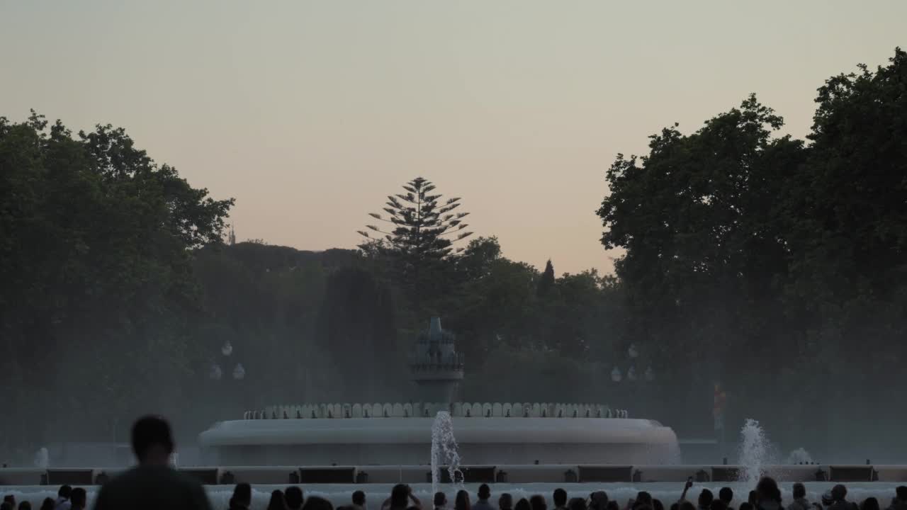 日落前拍摄的在西班牙加泰罗尼亚的巴塞罗那蒙特juic歌唱魔术喷泉的表演。在前景剪影的人。高质量4k镜头视频素材