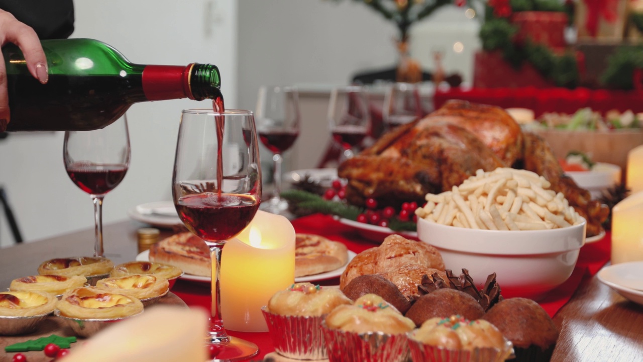 将红酒倒入餐桌上的玻璃杯里，庆祝圣诞节。视频素材