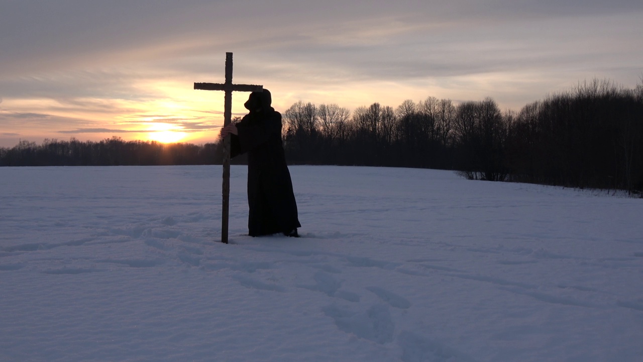 在雪夜的田野上，戴着黑色面具和十字架的鼠疫医生视频素材