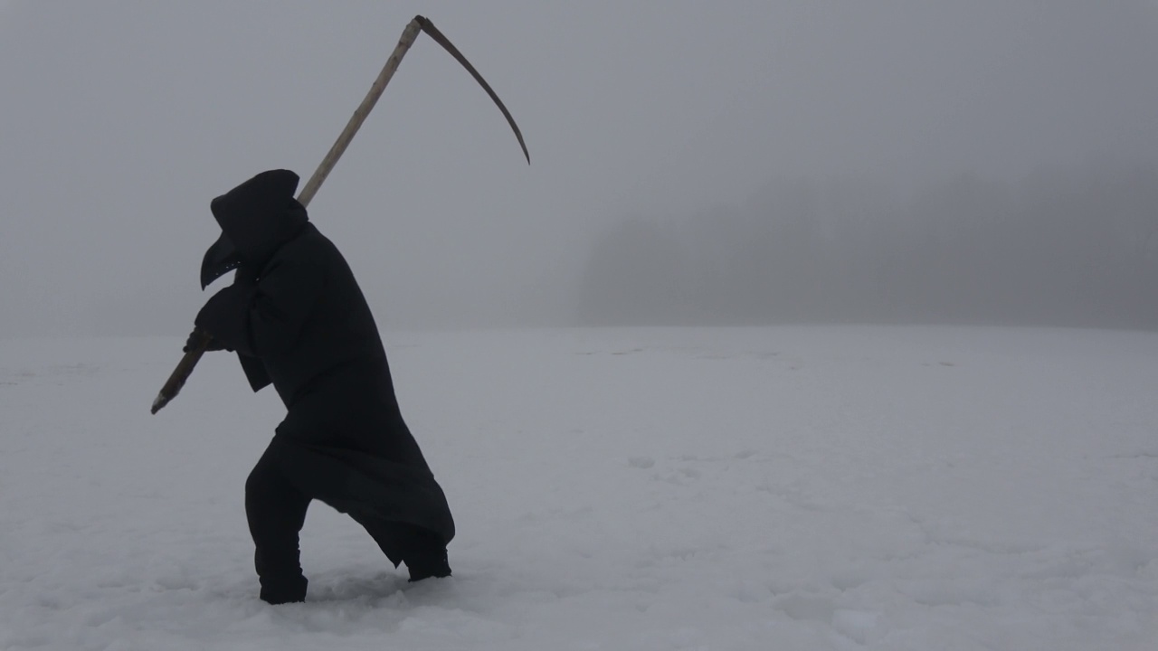 鼠疫医生戴着黑鸟嘴面具，手拿镰刀，在薄雾中穿过雪原视频素材