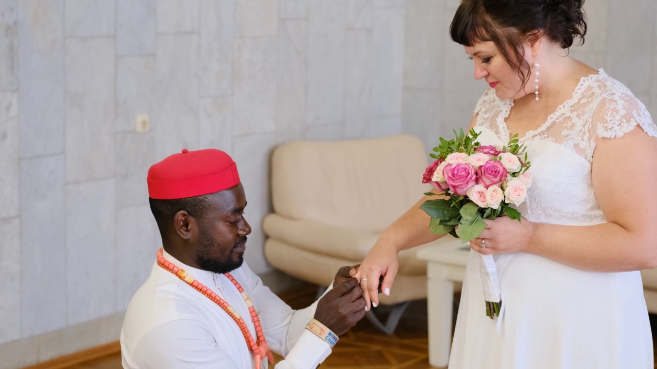 在婚礼上，非洲新郎把戒指戴在白人新娘的手指上。跨种族结婚视频素材
