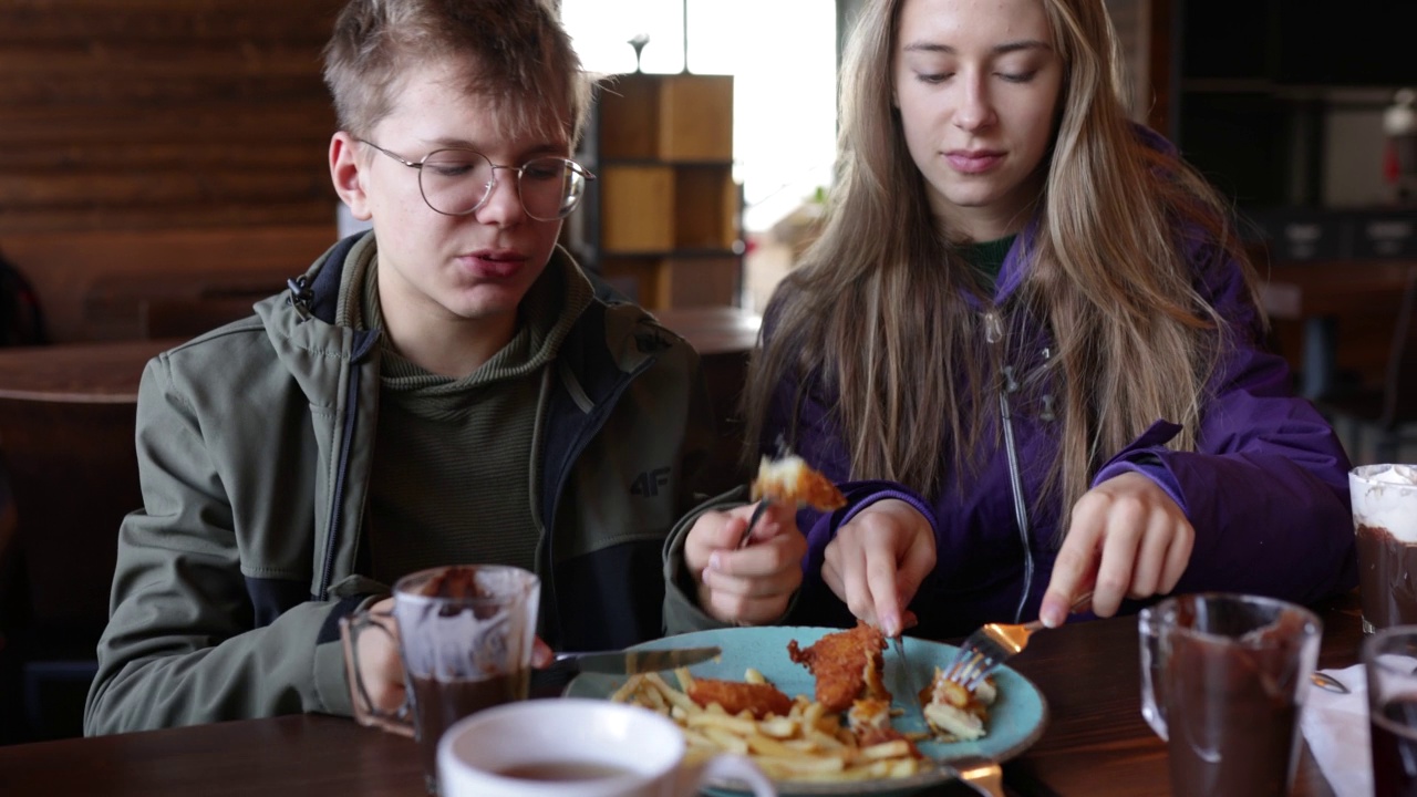在一家餐厅里享用鸡肉和炸薯条午餐的青少年视频素材
