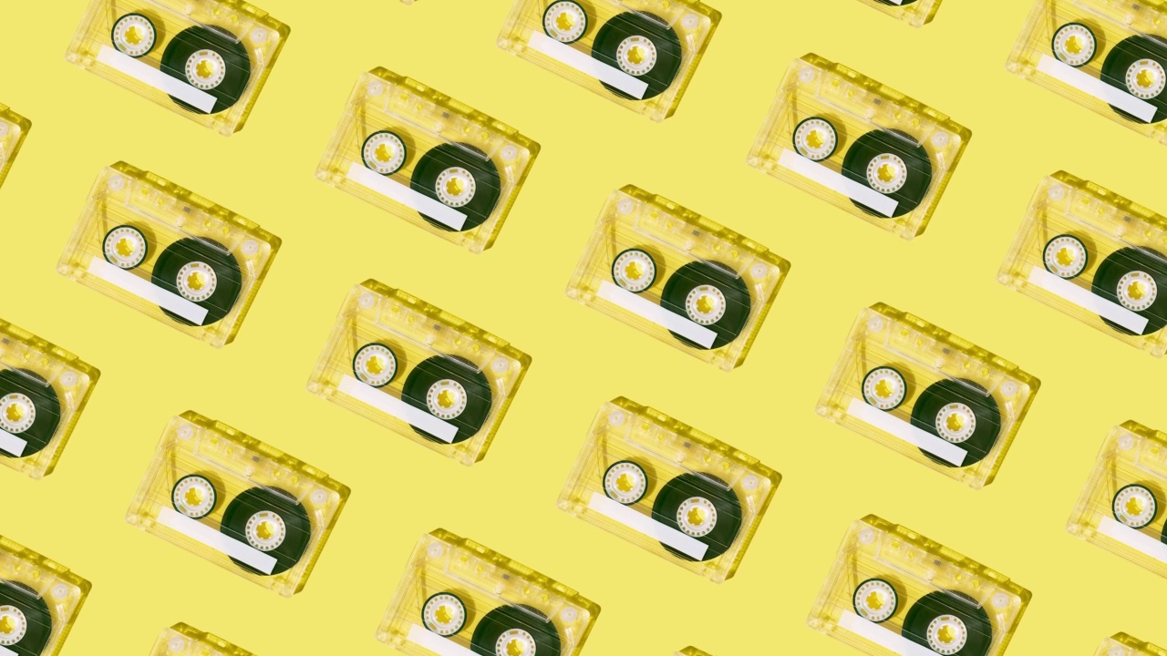 复古的模式与卡式磁带在充满活力的黄色背景。极简的怀旧音乐布局。视频素材