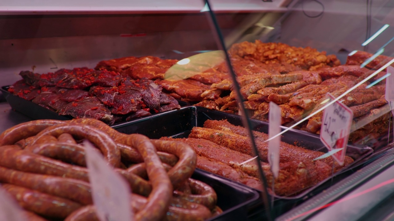 肉铺橱窗上挂着标签的新鲜生肉和卤肉。视频下载