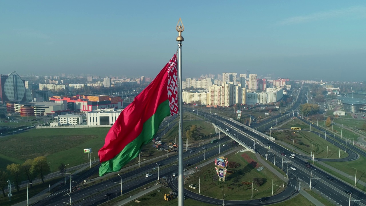 在一个阳光明媚的早晨，白俄罗斯国旗飘扬在湛蓝的天空和明斯克的城市风景上视频下载
