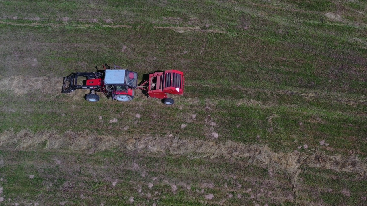 拖拉机使用拖捆机收集干草并制成卷，高空视频下载