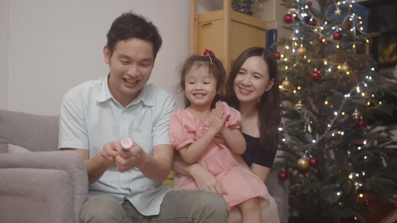 亚洲家庭在家里拉着聚会用的爆米花庆祝圣诞节。视频素材
