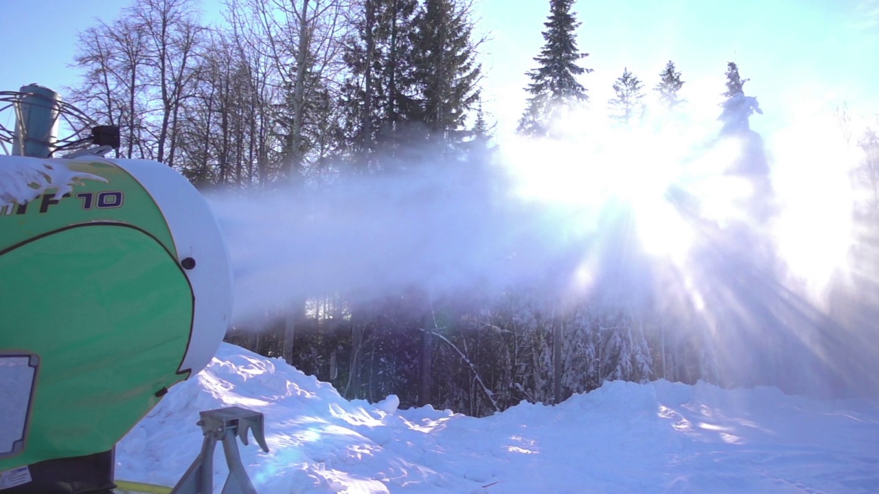 雪炮在迎着日出的斜坡上制造人造雪，慢镜头视频素材