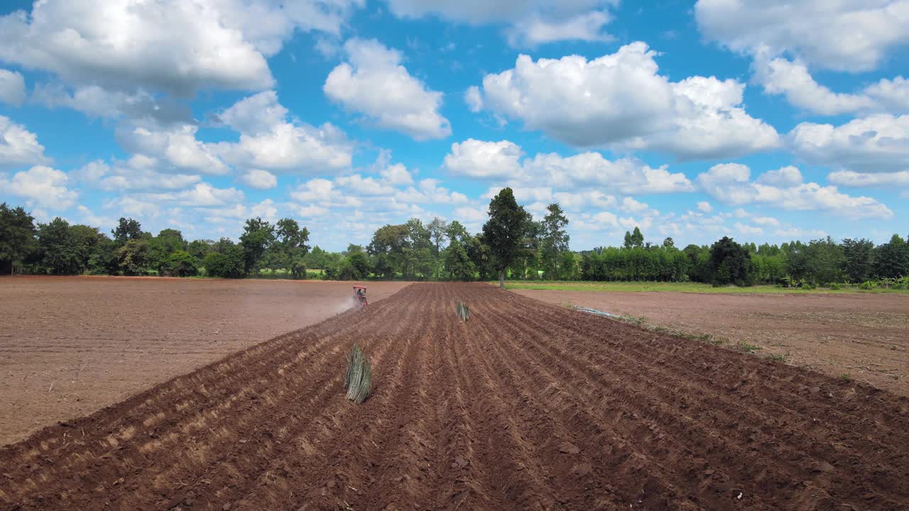 无人机摄影高角度拍摄，在木薯种植园。当时，拖拉机正在泰国一个农村小镇调整土壤，天气晴朗。视频下载