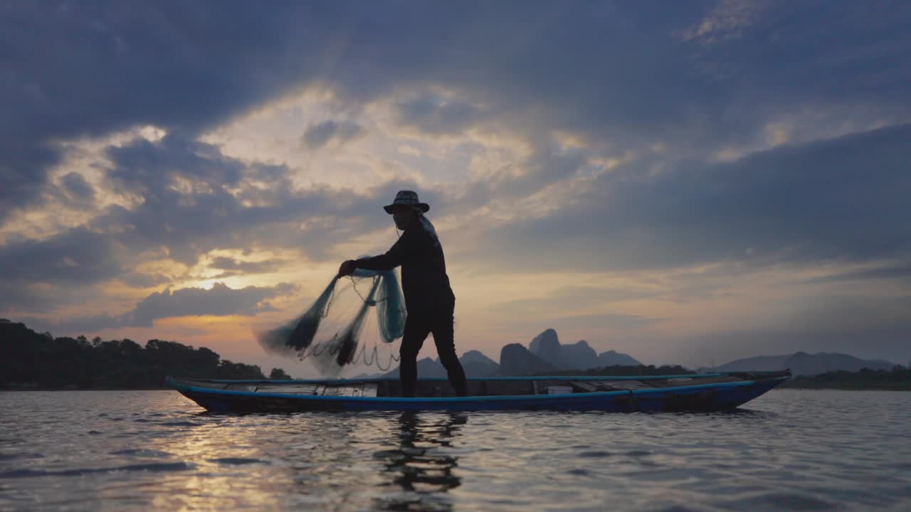 日落时分，渔民在湖边的船上抛渔网视频素材