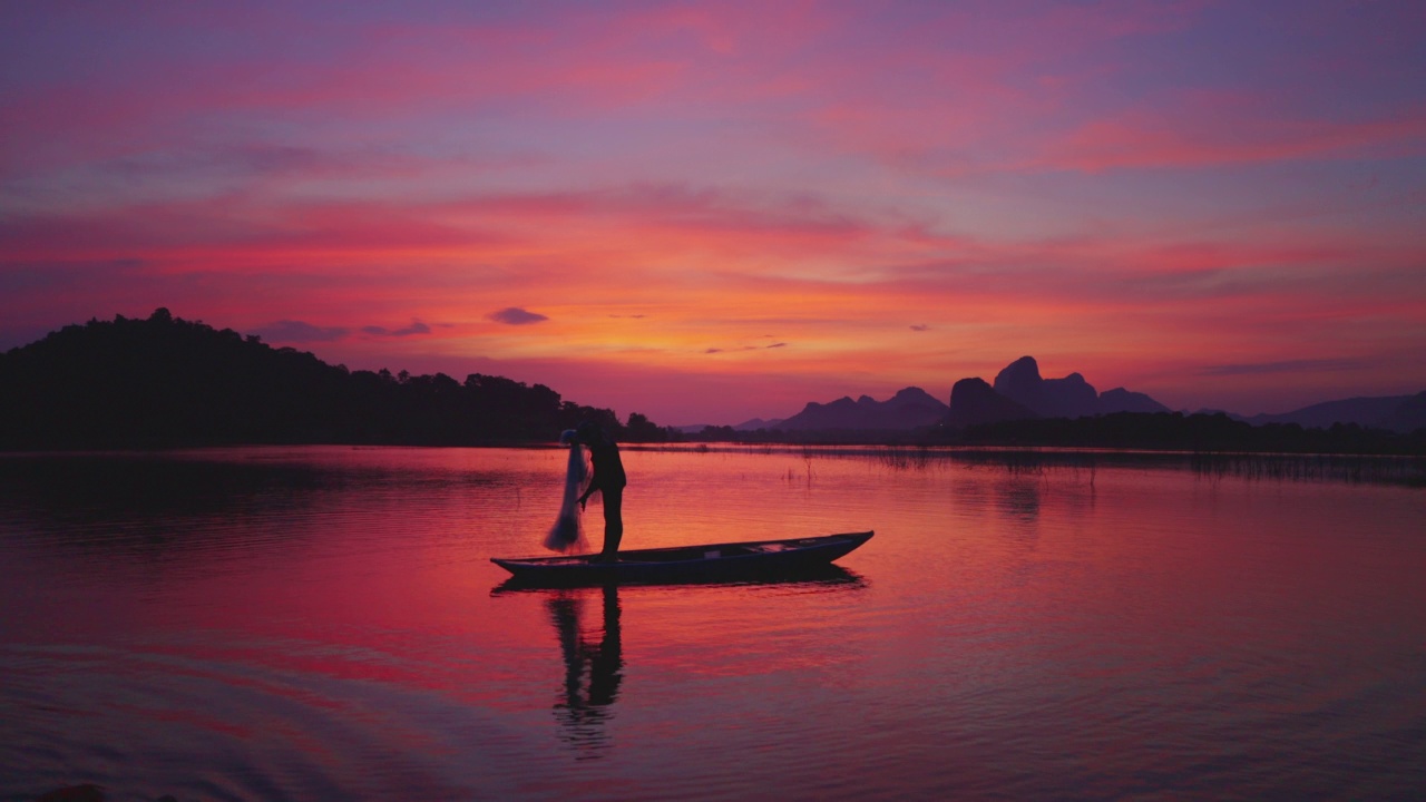 夕阳西下，渔夫在湖上的小船上准备渔网视频素材