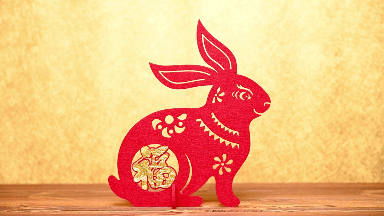 pan view中国新年兔子吉祥物剪纸在黄金背景在水平组成的汉字意味着财富没有标识没有商标视频素材