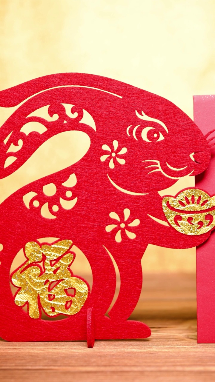 pan view中国新年兔子吉祥物剪纸与红色的口袋在金背景在垂直组成的汉字翻译是财富和好运没有标识没有商标视频素材