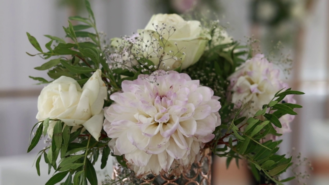 近装饰的餐桌与花瓶的花束白玫瑰，大丽花和绿色。来自婚礼活动的新鲜花束的花卉组成。节日花店在餐厅大厅视频素材