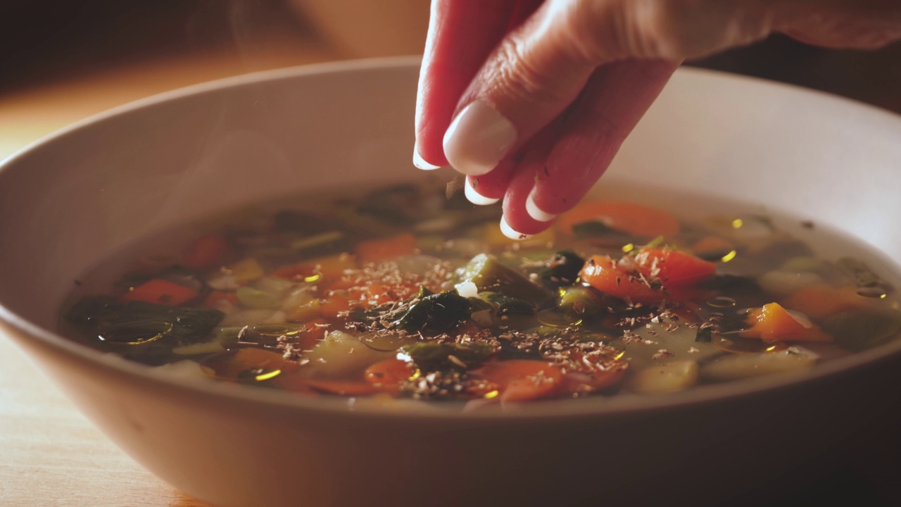 往意大利蔬菜浓汤里加香料。素菜汤已经上桌了。素食健康餐视频素材