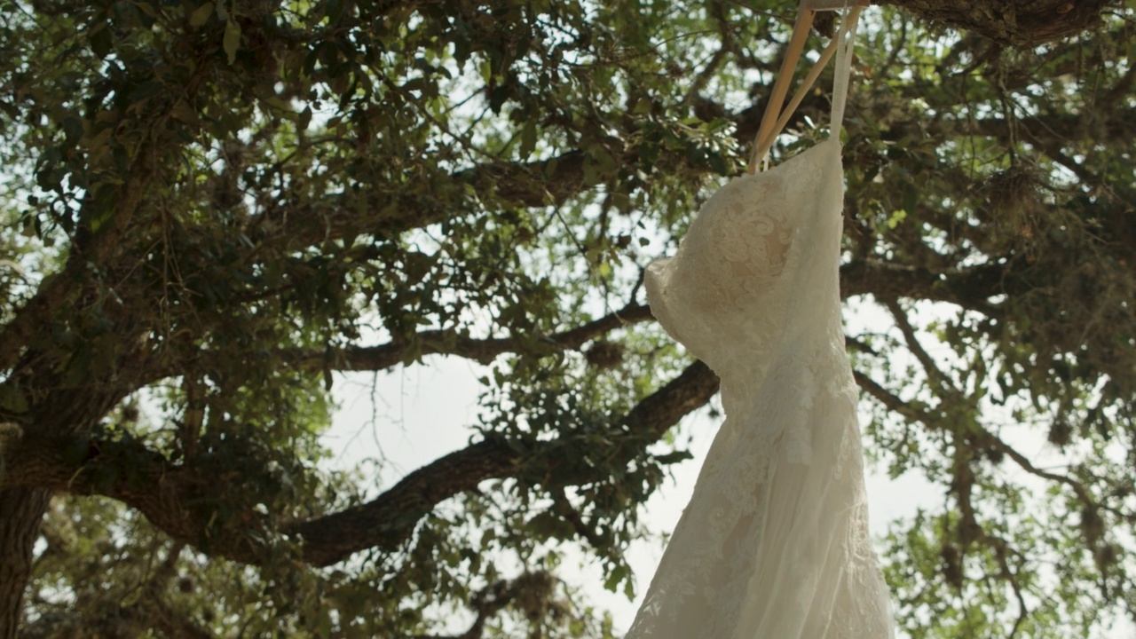 白色的婚纱挂在挂在花园里树上的衣架上视频素材
