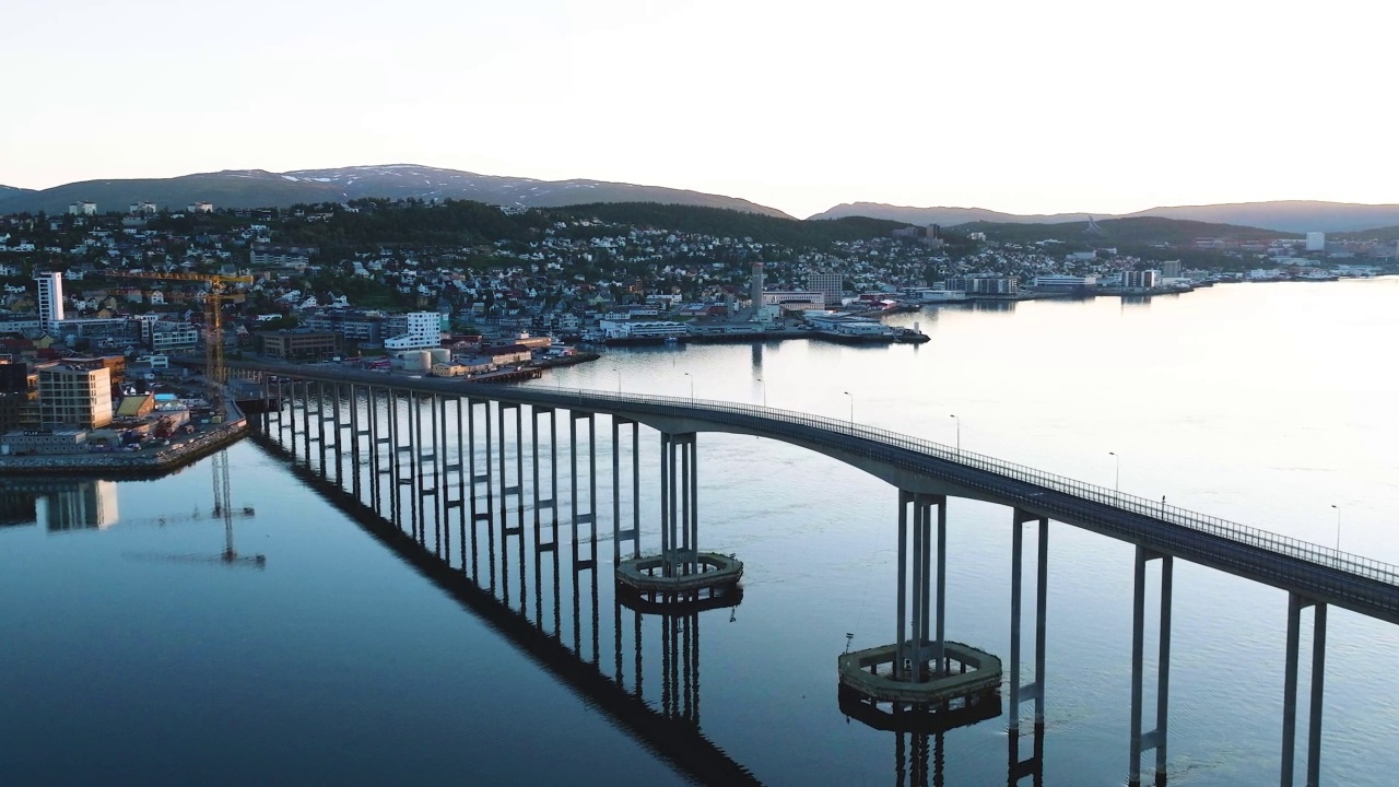 在挪威特罗姆瑟的城市背景上，一座桥和海上的船只的空中慢动作视频下载