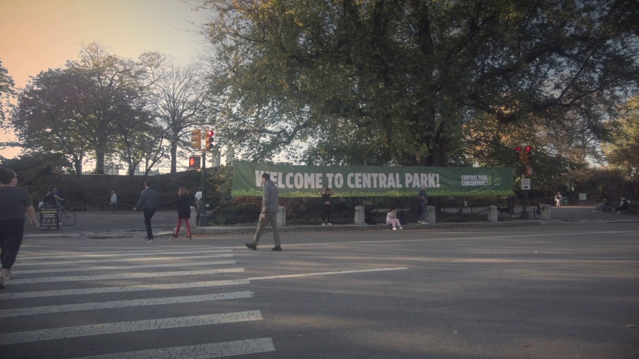 中央公园的秋天，人们走过一个巨大的欢迎标志视频下载