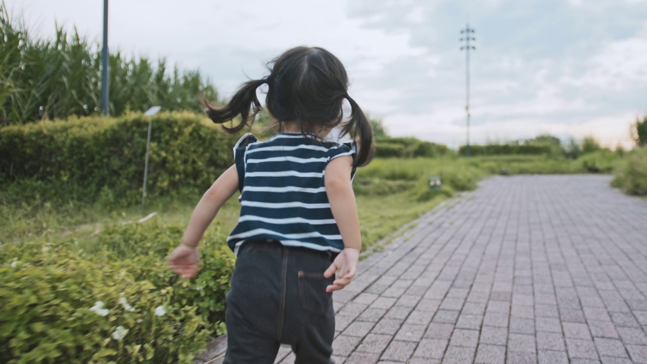 年轻的亚洲白人混合种族的女孩喜欢在公园里跑步，后视图。快乐的童年生活。健康儿童概念视频下载