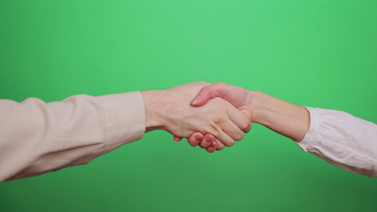 绿色背景下的商务人士握手特写。人们在握手。视频下载