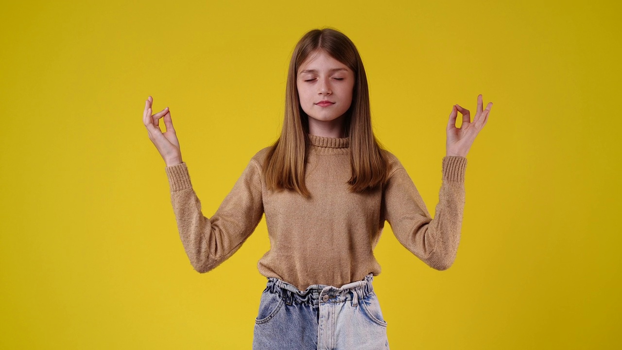 一个女孩在黄色背景下冥想的4k视频。视频下载