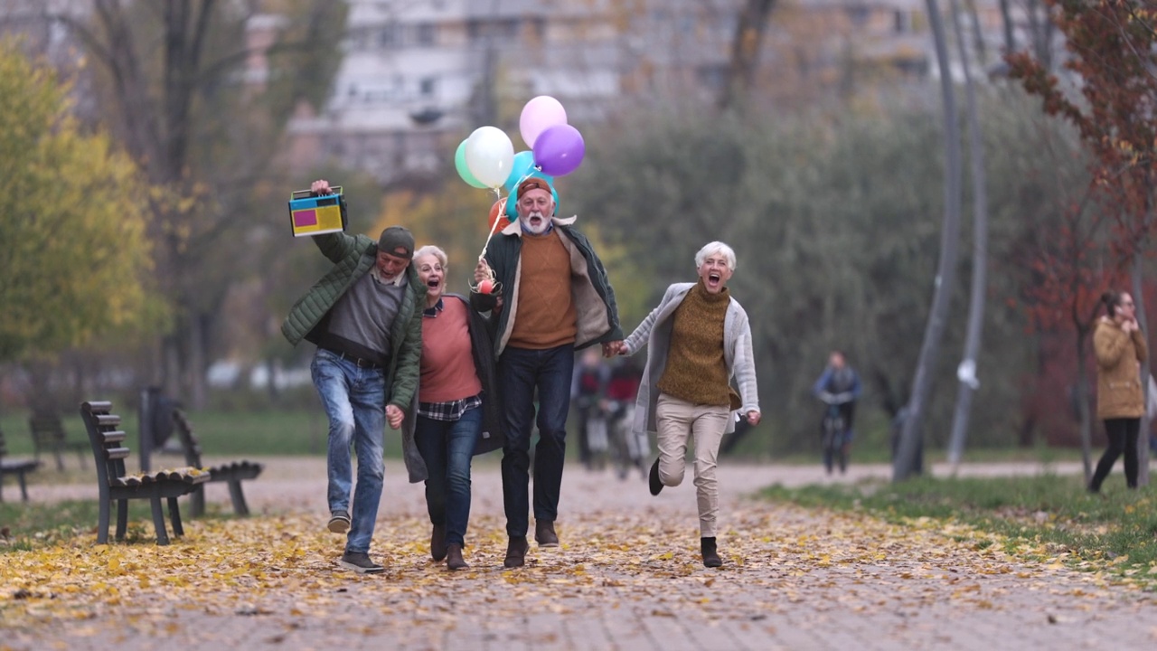 快乐的老夫妇在公园里跳气球。视频素材