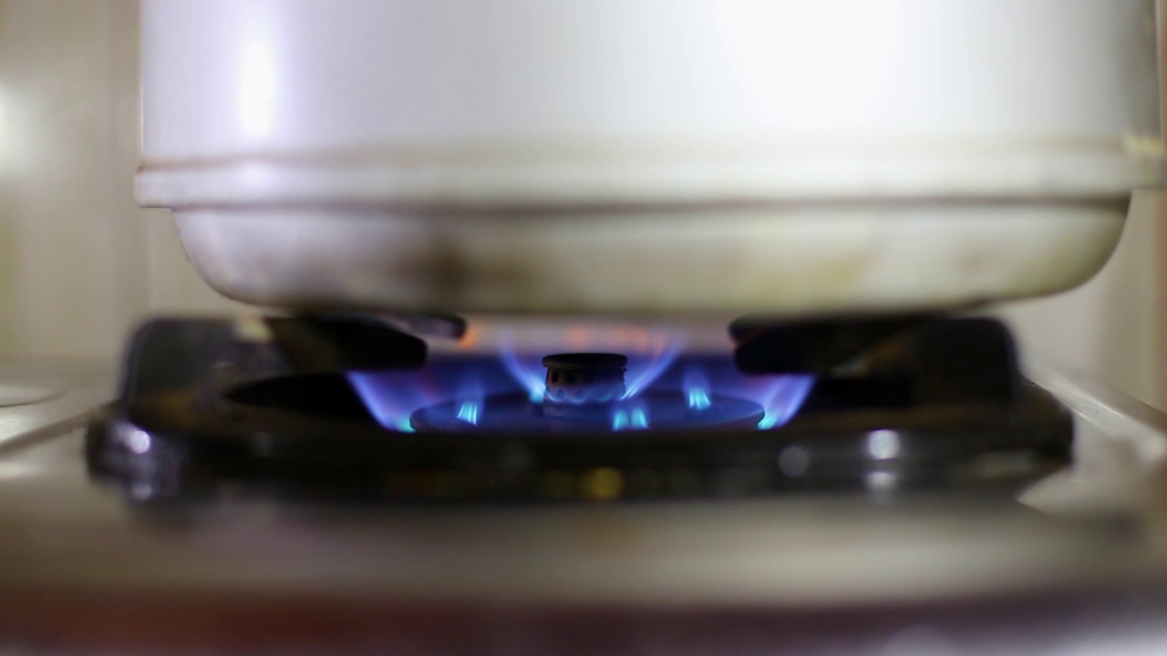 煤气炉上装有开水的茶壶。从厨房煤气炉中燃烧的煤气视频素材