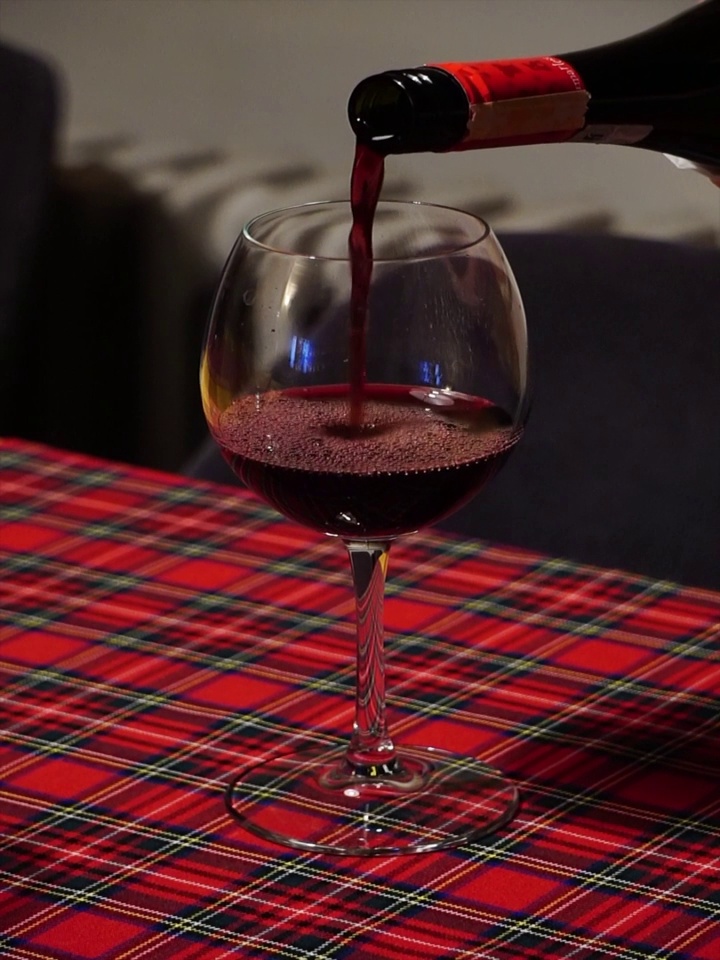 垂直视角，一只手在玻璃杯里倒着一瓶极好的红酒视频素材