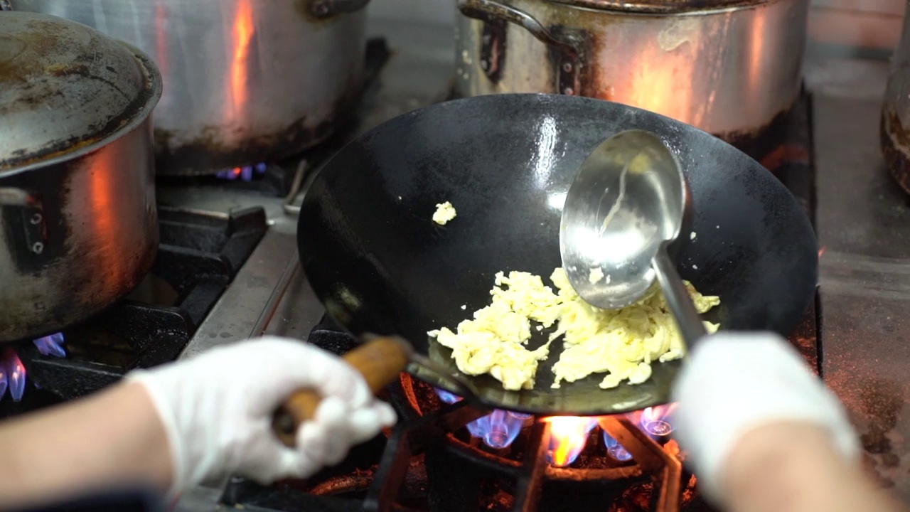 男人的手，把煎锅放在火上，里面有一个炒鸡蛋，慢动作。视频下载
