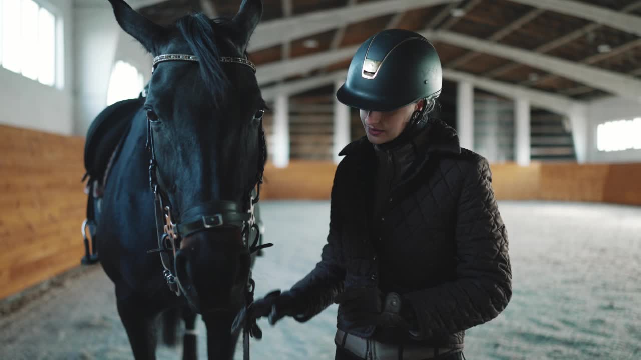 严肃的女骑手戴着头盔和马一起走视频下载