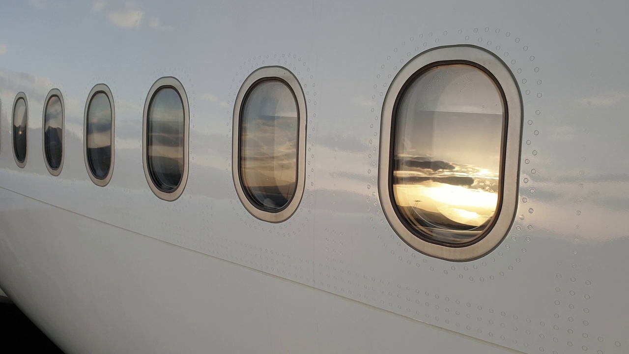 黄昏时飞机舷窗和铆钉的特写。平移视频下载