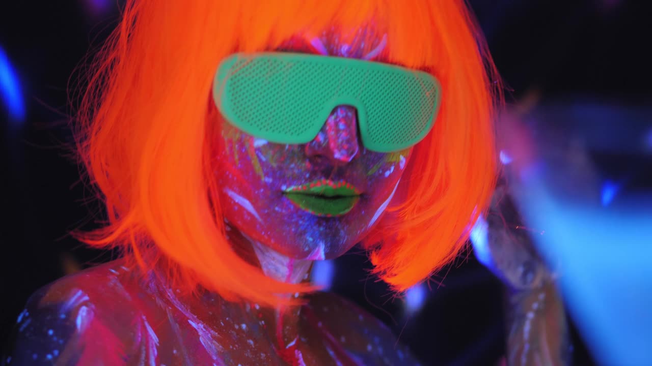 一个戴着橙色假发，戴着马蒂尼酒杯，带着紫外线图案的女孩。视频下载