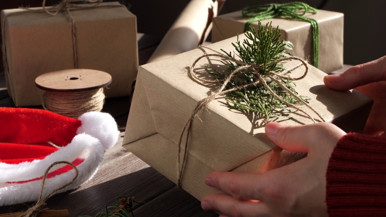 双手包裹环保圣诞礼物。无塑料和可持续包装。再生纸和麻绳弓。视频下载