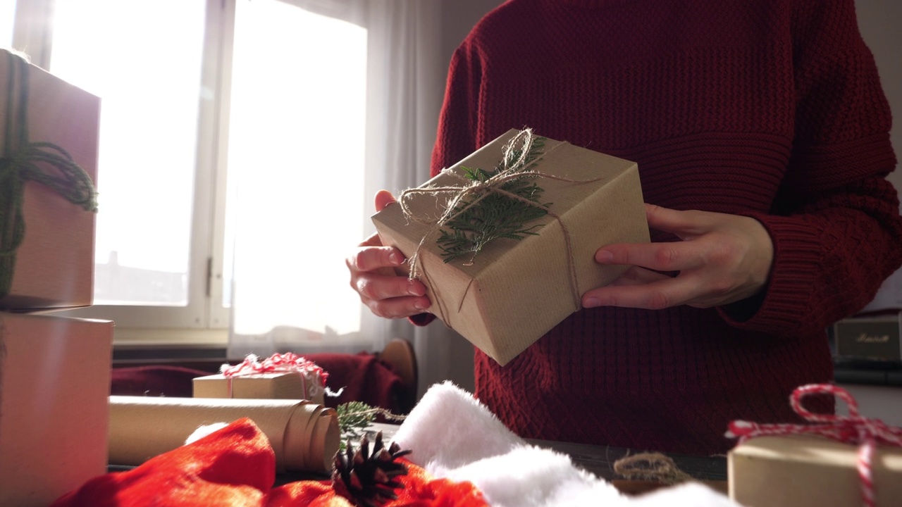 手拿着用回收的礼物纸包装的圣诞礼物视频下载