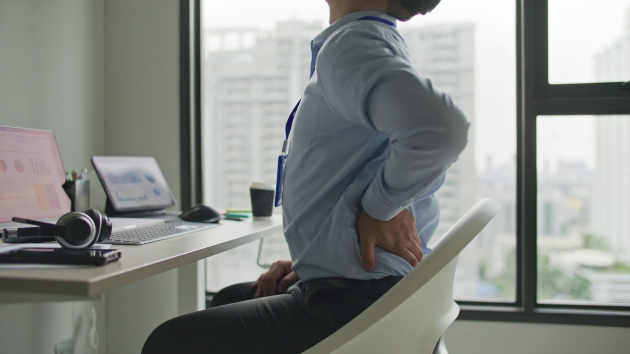 年轻的商人在办公室办公桌上工作时背部疼痛视频素材