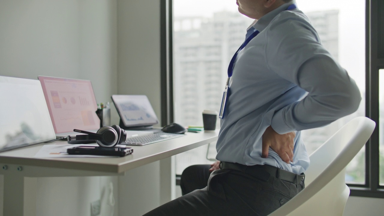 年轻的商人在办公室办公桌上工作时背部疼痛视频素材