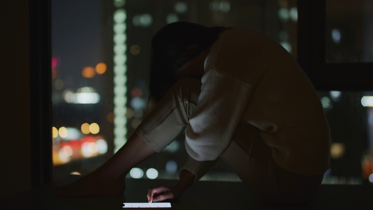 抑郁的十几岁女孩坐在黑暗房间的地板上视频素材